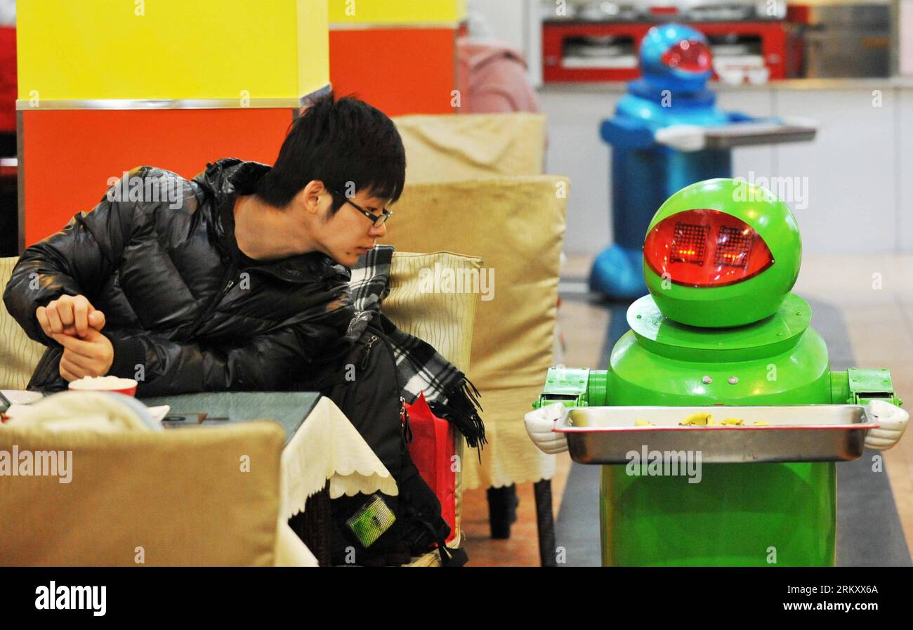 Bildnummer: 59103142 Datum: 18.01.2013 Copyright: imago/Xinhua (130118) -- HARBIN, 18 gennaio 2013 (Xinhua) -- Un cliente guarda un robot che serve piatti in un ristorante a tema robot a Harbin, capitale della provincia di Heilongjiang della Cina nord-orientale, 18 gennaio 2013. Aperto nel giugno del 2012, il ristorante ha guadagnato fama utilizzando un totale di 20 robot per cucinare i pasti, consegnare i piatti e salutare i clienti. (Xinhua/Wang Jianwei) (zc) RISTORANTE A TEMA CHINA-HEILONGJIANG-HARBIN-ROBOT (CN) PUBLICATIONxNOTxINxCHN Gesellschaft Gastronomie Erlebnisgastronomie kurios Komik Roboter Kellner Fotostory x0x xds 2013 qu Foto Stock