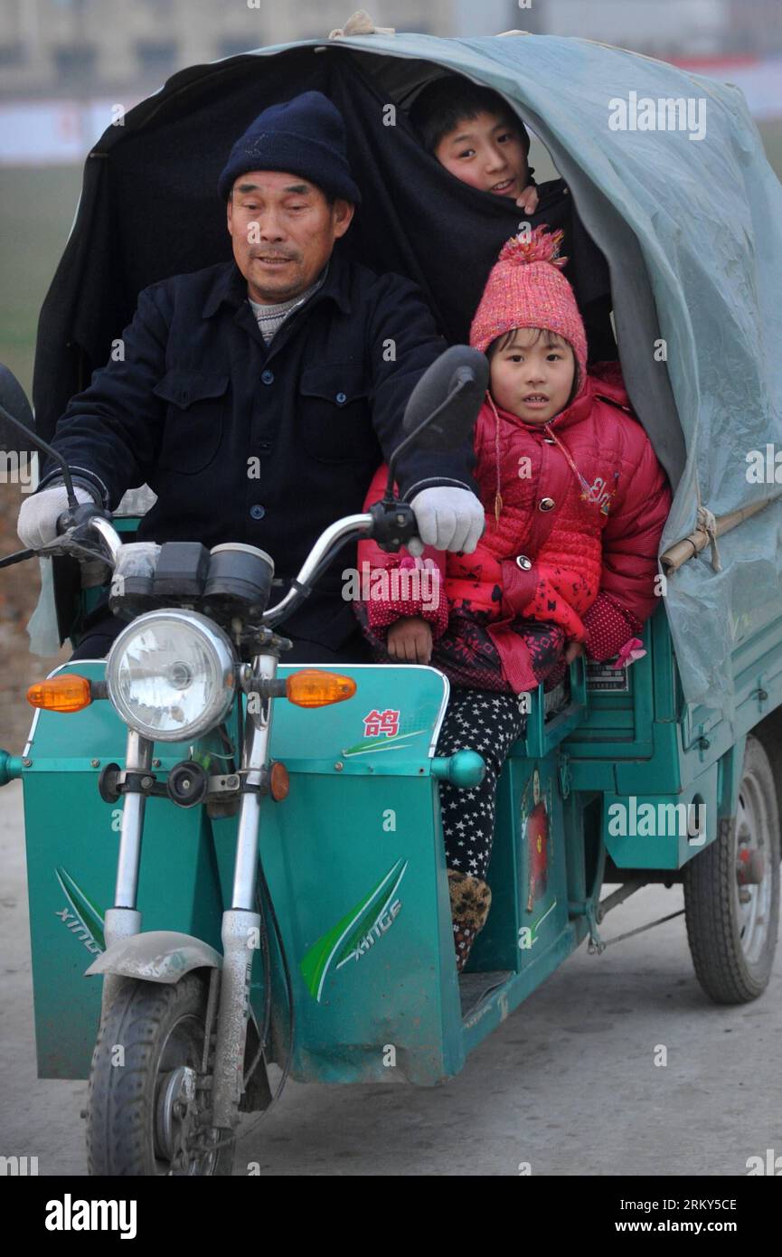 Bildnummer: 59148637 Datum: 29.01.2013 Copyright: imago/Xinhua HANGZHOU, gennaio 28, 2013 -- Liu Zhen (indietro) guarda come sua sorella minore Liu Pingping (fronte R) siede sul triciclo del nonno sul sentiero nel loro villaggio nel distretto di Yingzhou, città di Fuyang nella provincia di Anhui della Cina orientale, 29 gennaio 2013. Liu Chuantao, un lavoratore migrante di 32 anni, gestisce un'attività di decorazione domestica a Hangzhou, capitale della provincia di Zhejiang nella Cina orientale. Sua moglie, Chen Yan, lavora per una fabbrica con sede a Hangzhou. La coppia portò la loro figlia di otto anni Liu Pingping a Hangzhou. Mentre lasciavano loro Foto Stock