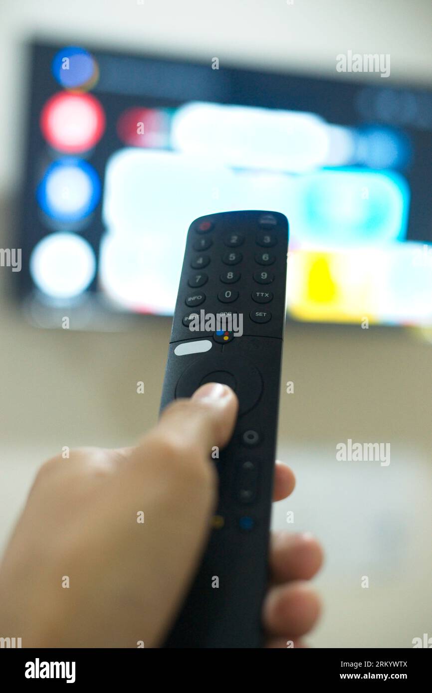 Grazie al telecomando TV, puoi passare da una serie TV all'altra dalla piattaforma di servizi di streaming. Il nuovo modo di godersi l'intrattenimento a casa. Foto Stock