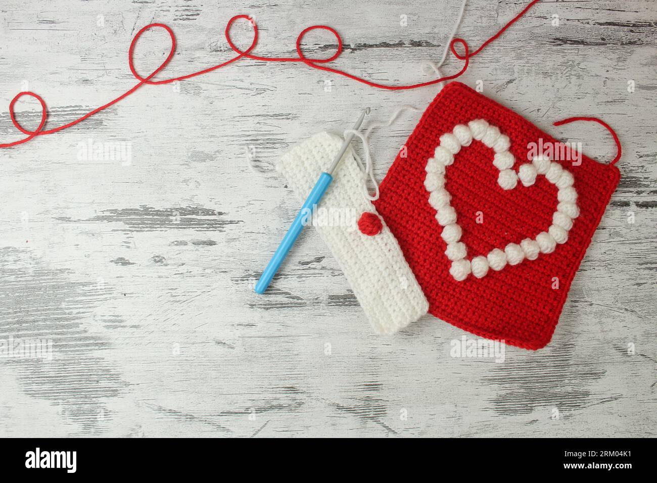 Motivi a forma di popcorn a forma di cuore per coperte a uncinetto in rosso e bianco con spazio per il testo. Vista dall'alto. Foto Stock