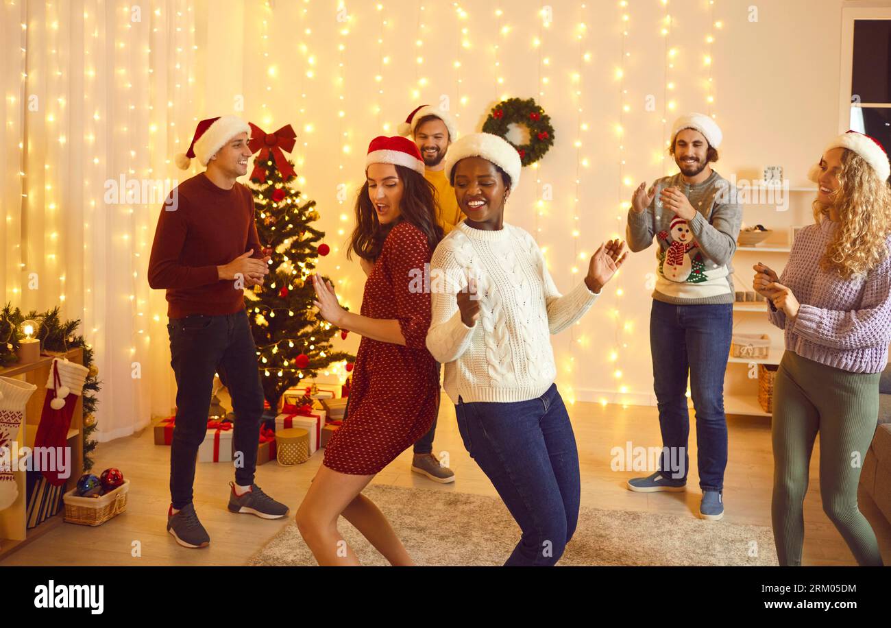 Felicissimi amici multirazziali ballano alla festa di Natale Foto Stock