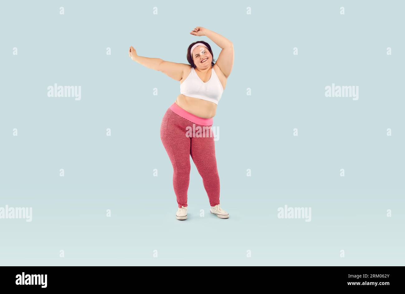 Foto completa di una donna obesa e in sovrappeso felice che celebra il progresso della perdita di peso Foto Stock