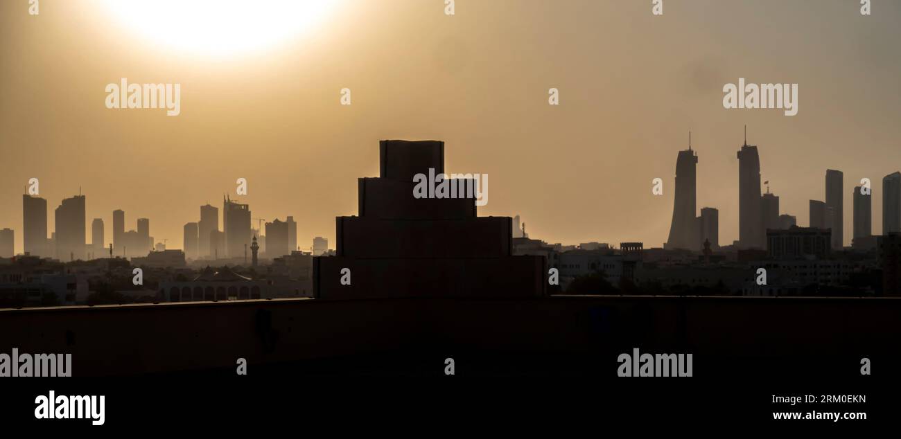 Profilo skyline del Bahrain contro il sole che tramonta Foto Stock