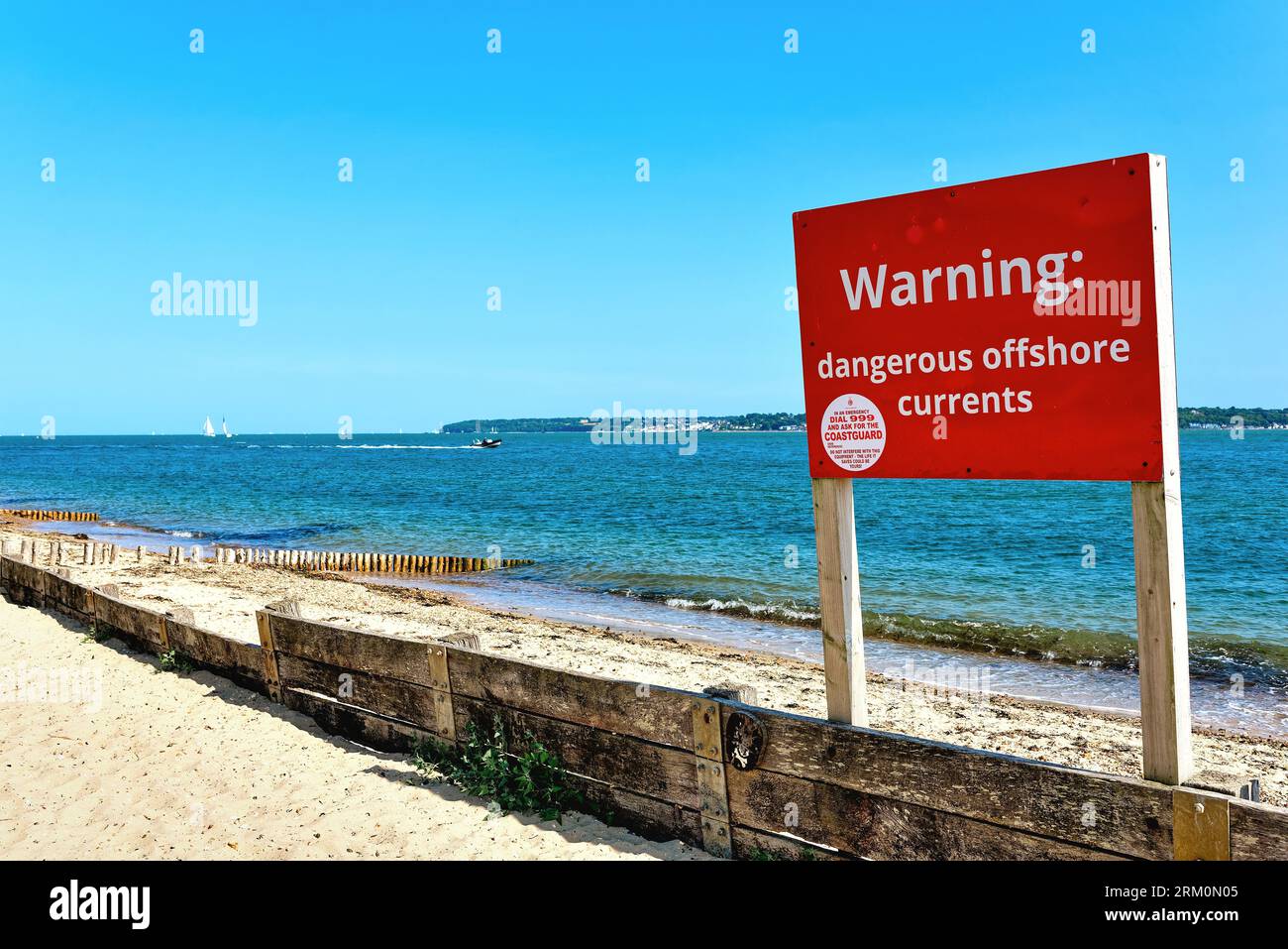Un grande cartello rosso sulla spiaggia avverte il pubblico di "Dangerous Offshore Currents" al Lepe Country Park in un giorno estivo Hampshire Inghilterra Regno Unito Foto Stock