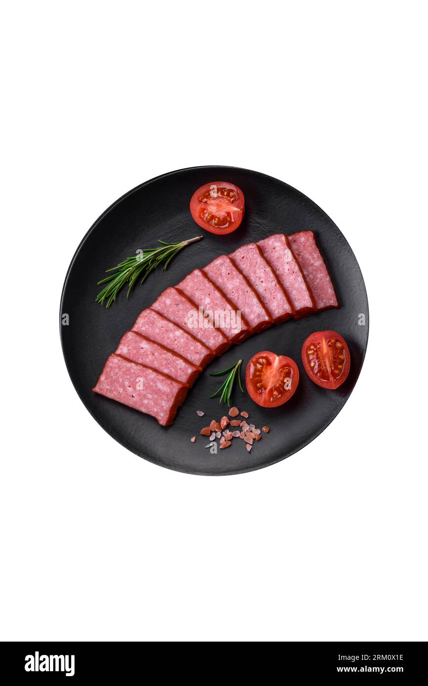 Delizioso salame di salsiccia fresco con sale, pomodori e spezie su fondo di cemento scuro Foto Stock