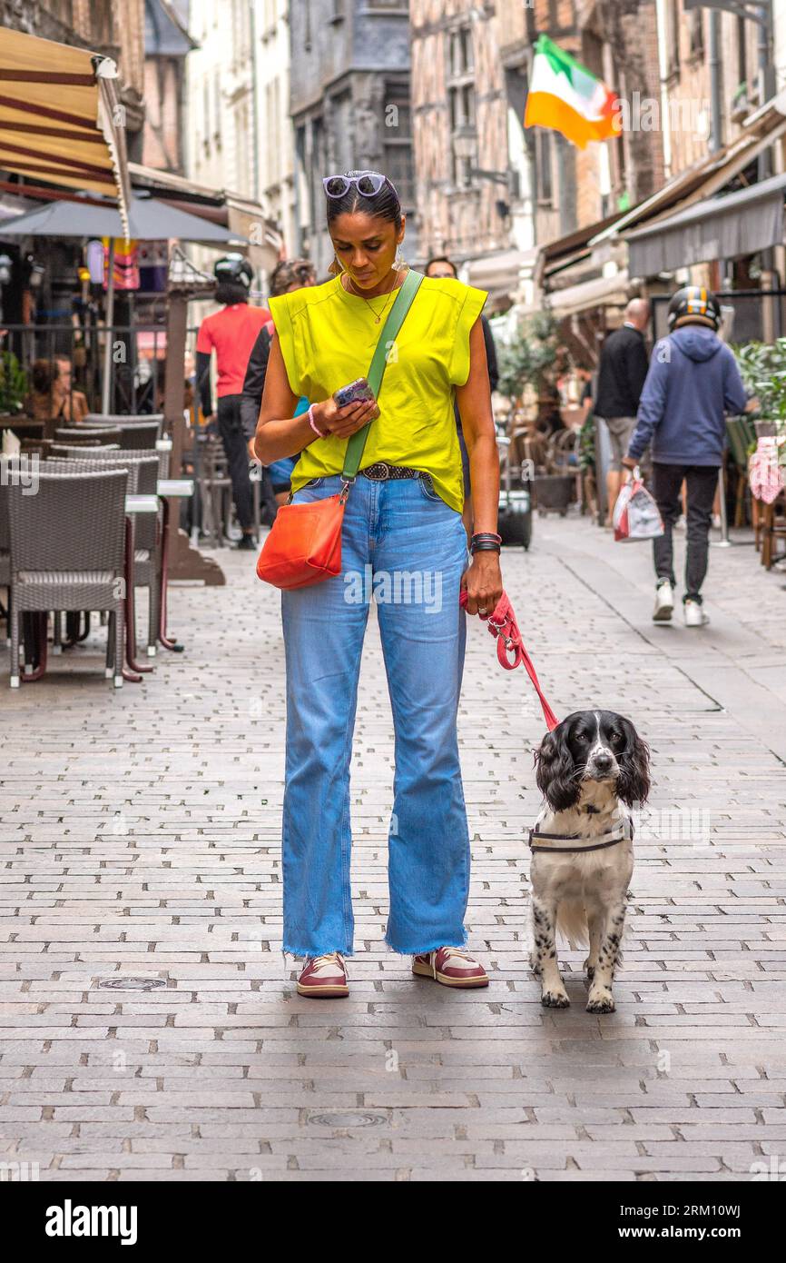Donna alta con cane che controlla il suo smartphone in centro - Tours, Indre-et-Loire (37), Francia. Foto Stock