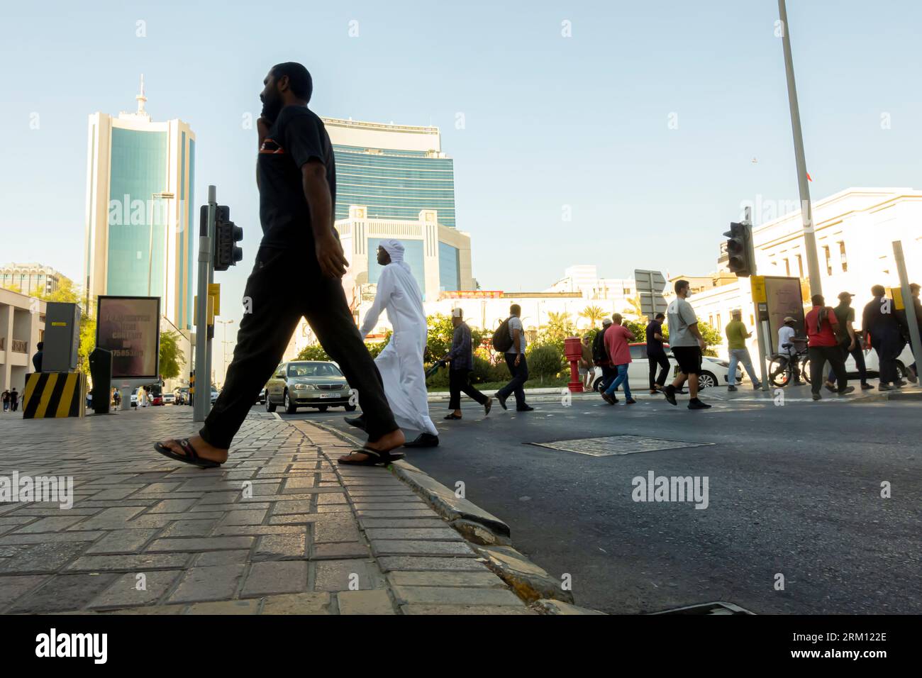 Persone che attraversano la strada a Manama Bahrain, i pedoni attraversano la strada in Bahrain. La gente attraversa la strada nel centro di al Khalifa ave Manama Bahrain Foto Stock