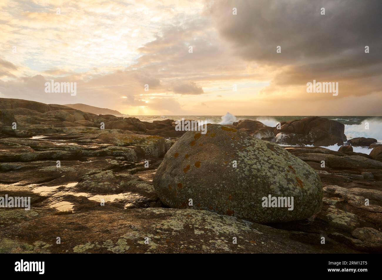 Costa rocciosa della Costa da morte con mare spiovente e onde infranti al tramonto (Muxía, Fisterra, A Coruña, Galizia, Mar Atlantico, Spagna) Foto Stock