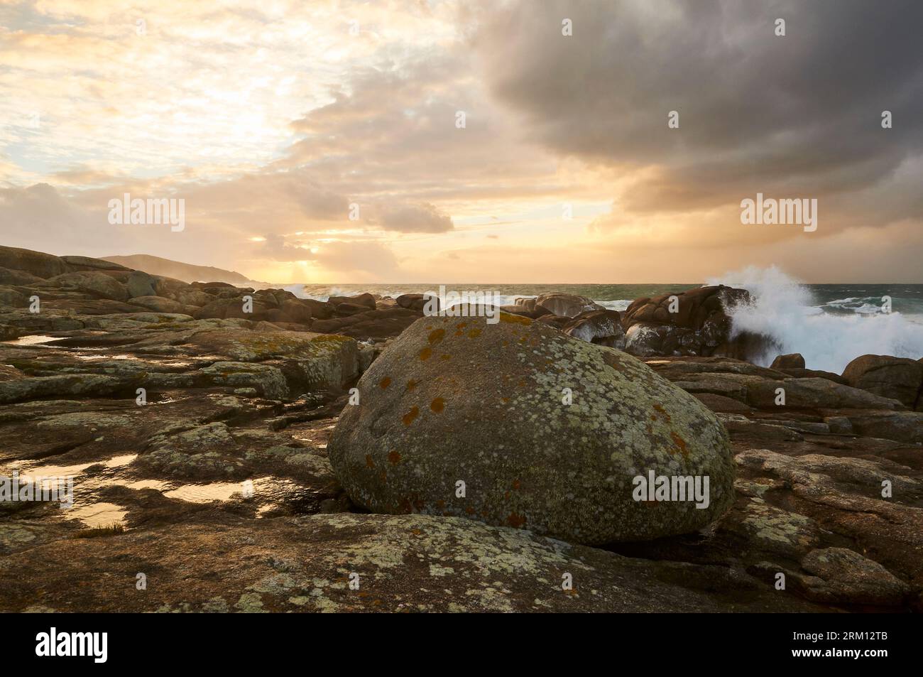 Costa rocciosa della Costa da morte con mare spiovente e onde infranti al tramonto (Muxía, Fisterra, A Coruña, Galizia, Mar Atlantico, Spagna) Foto Stock