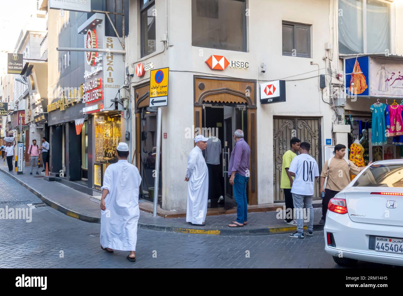Gli uomini aspettano in fila per il bancomat HSBC nella filiale di Manama, nel Bahrain Foto Stock