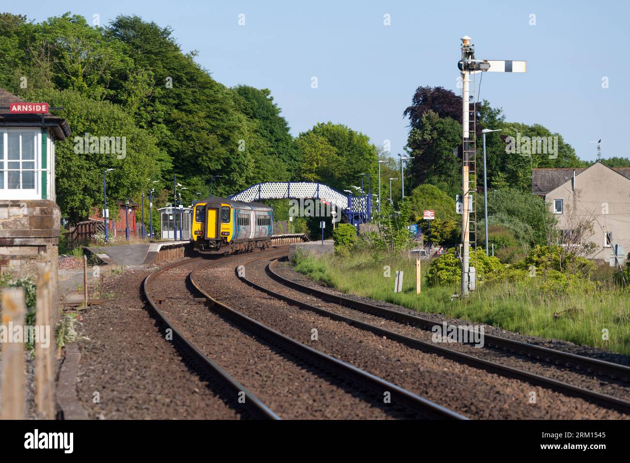 Treno velocista Northern Rail classe 156 alla stazione ferroviaria di Arnside con segnale ferroviario a semaforo Foto Stock