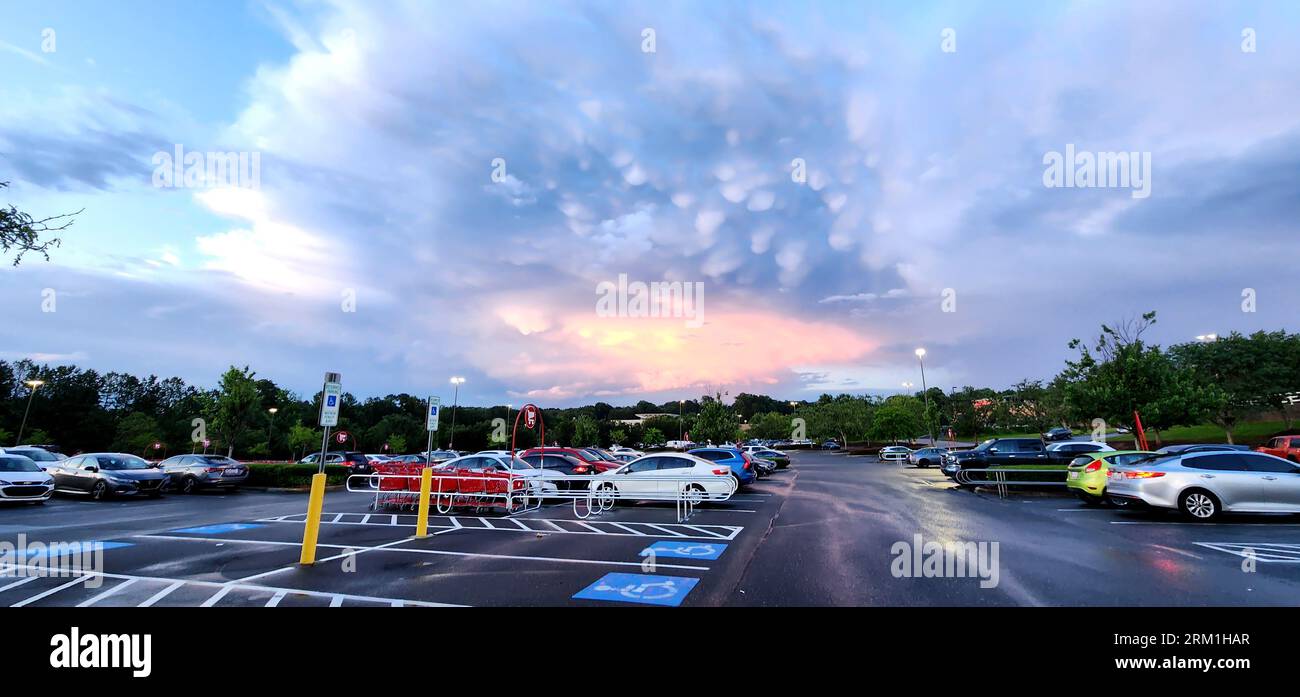 Fuori in un parcheggio con auto durante le ore serali, con il sole che tramonta e le nuvole riempiono il cielo (NC State, 2023) Foto Stock