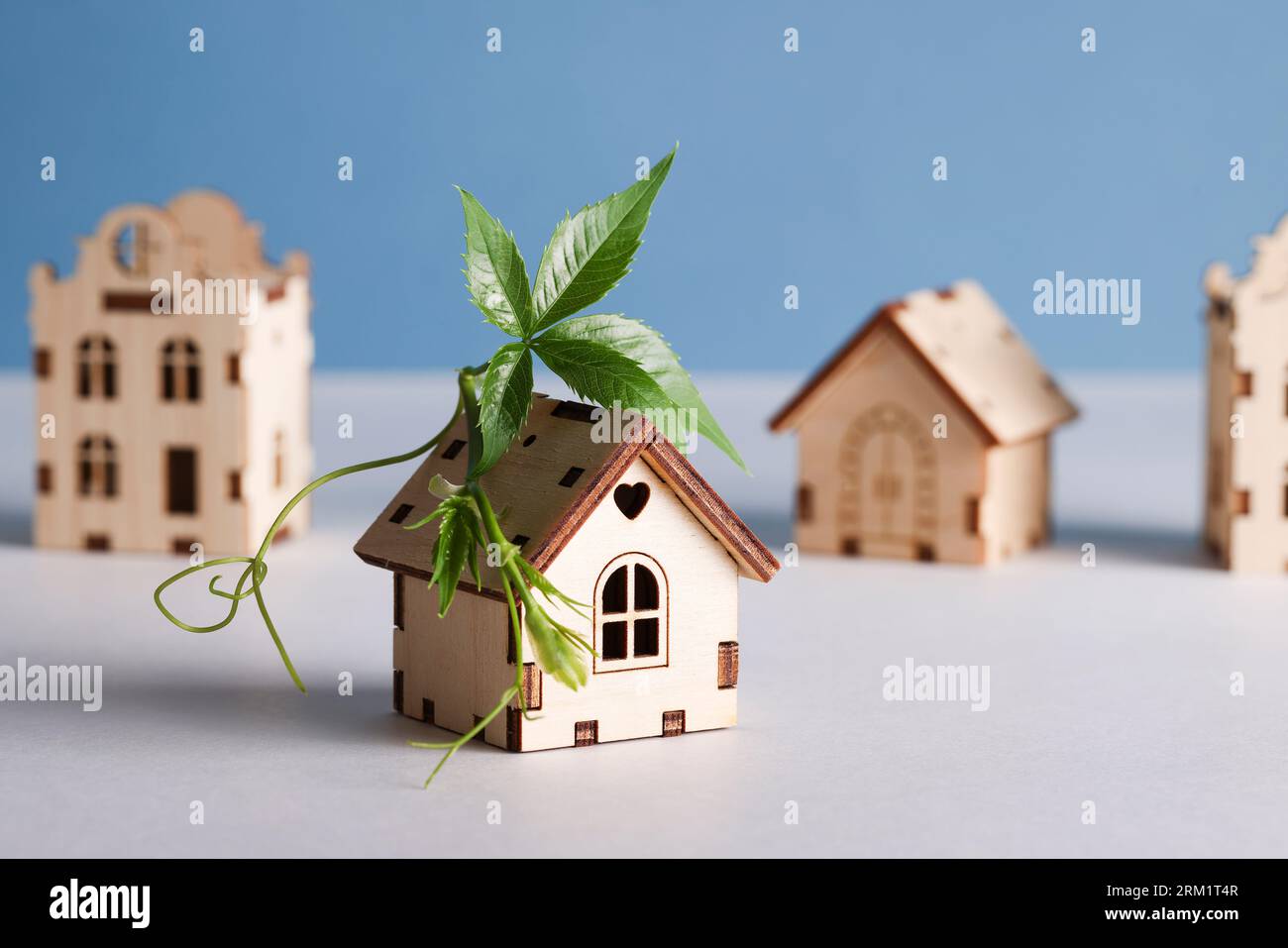 movimento retrofit, case a prova di futuro, zero emissioni nette di carbonio, adattamento del concetto degli edifici. case dei giocattoli con foglie verdi sul tetto su sfondo blu. Foto Stock