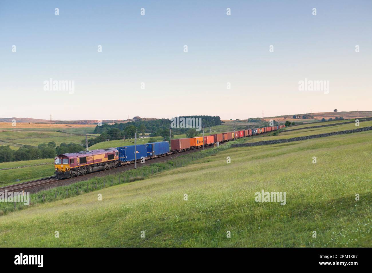 Locomotiva diesel DB cargo classe 66 sulla linea principale elettrificata della costa occidentale a Shap in Cumbria con un convoglio intermodale Foto Stock