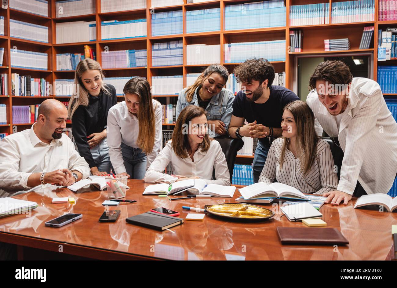 Due professori e i loro studenti ridono e si divertono in una biblioteca Foto Stock