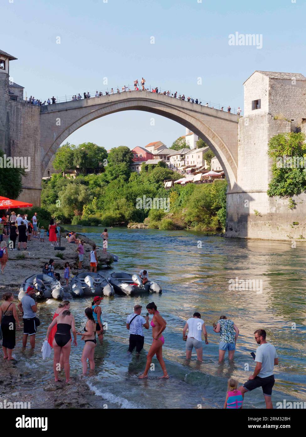 Stari Most (Ponte Vecchio) lungo il fiume Neretva con turisti sulla spiaggia sottostante. Città di Mostar, Bosnia ed Erzegovina, 26 agosto 2023. Foto Stock