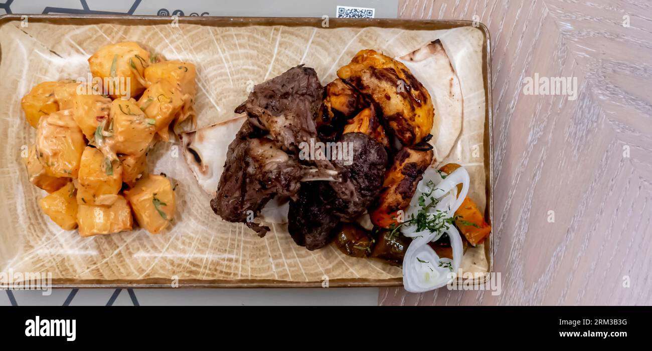 Grigliate miste di carne - costolette di agnello, kebab di pollo e manzo, patate arrosto alle erbe e verdure sottaceto - ristorante Crossroads Bahrain Foto Stock