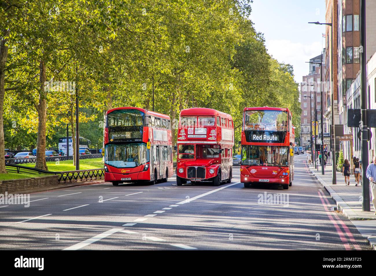 Tre generazioni di autobus rossi della città di Londra guidano a Mayfair vicino a Hyde Park Foto Stock