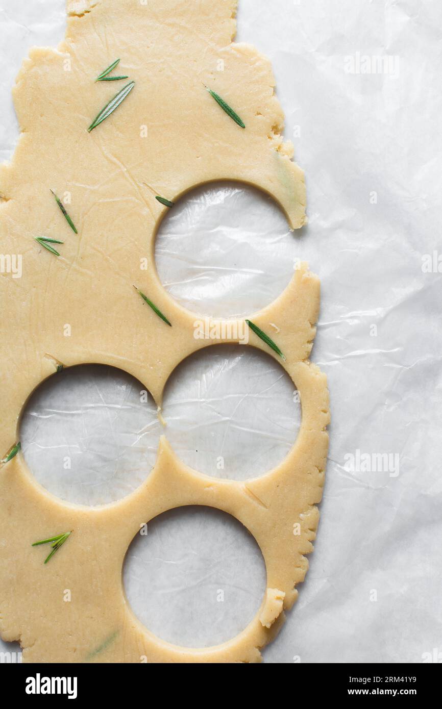 Vista dall'alto di tagliare l'impasto dei biscotti allo zucchero al rosmarino, l'impasto dei biscotti alle erbe e il processo di preparazione dei biscotti allo zucchero Foto Stock