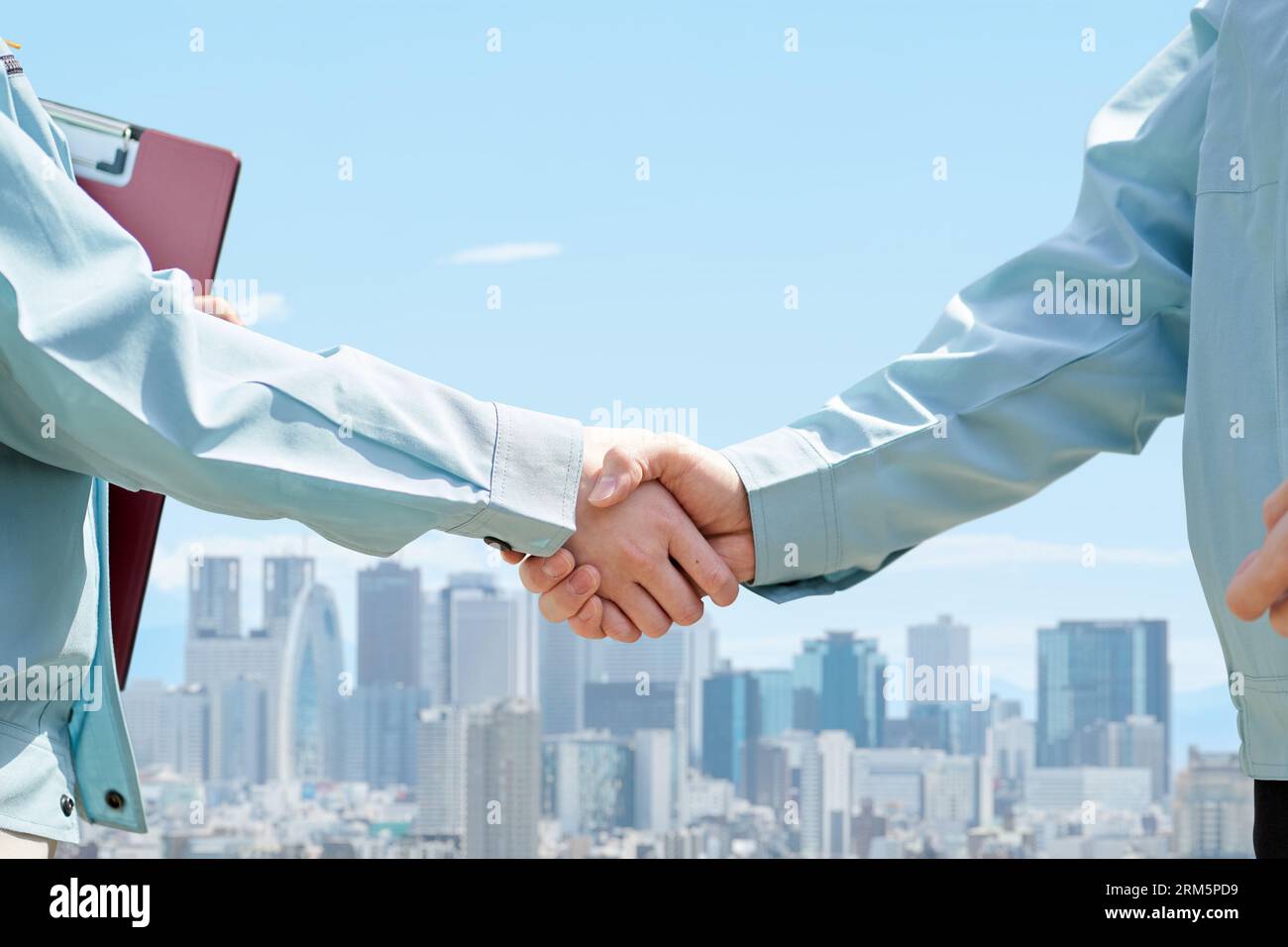 Operai edili che stringono la mano sullo sfondo della città Foto Stock