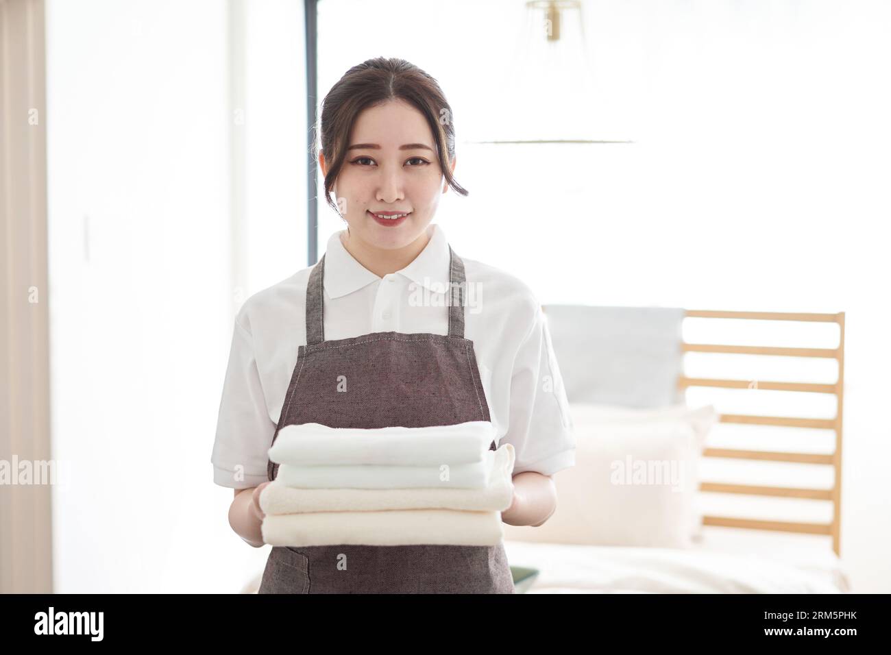 Donna asiatica che piega gli asciugamani e li mette via Foto Stock