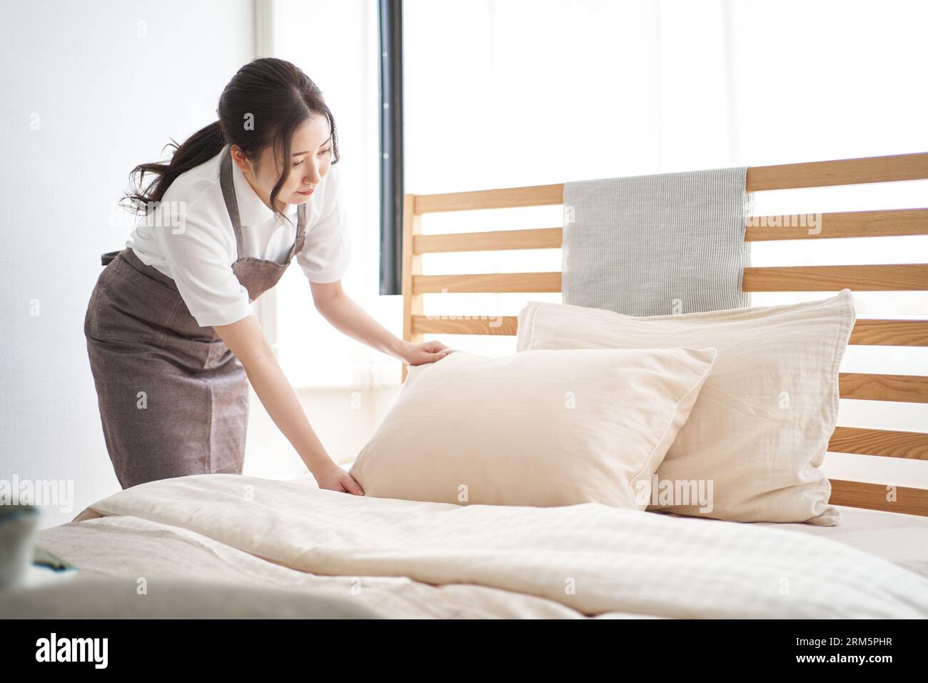 Donna asiatica che fa un letto in camera da letto Foto Stock