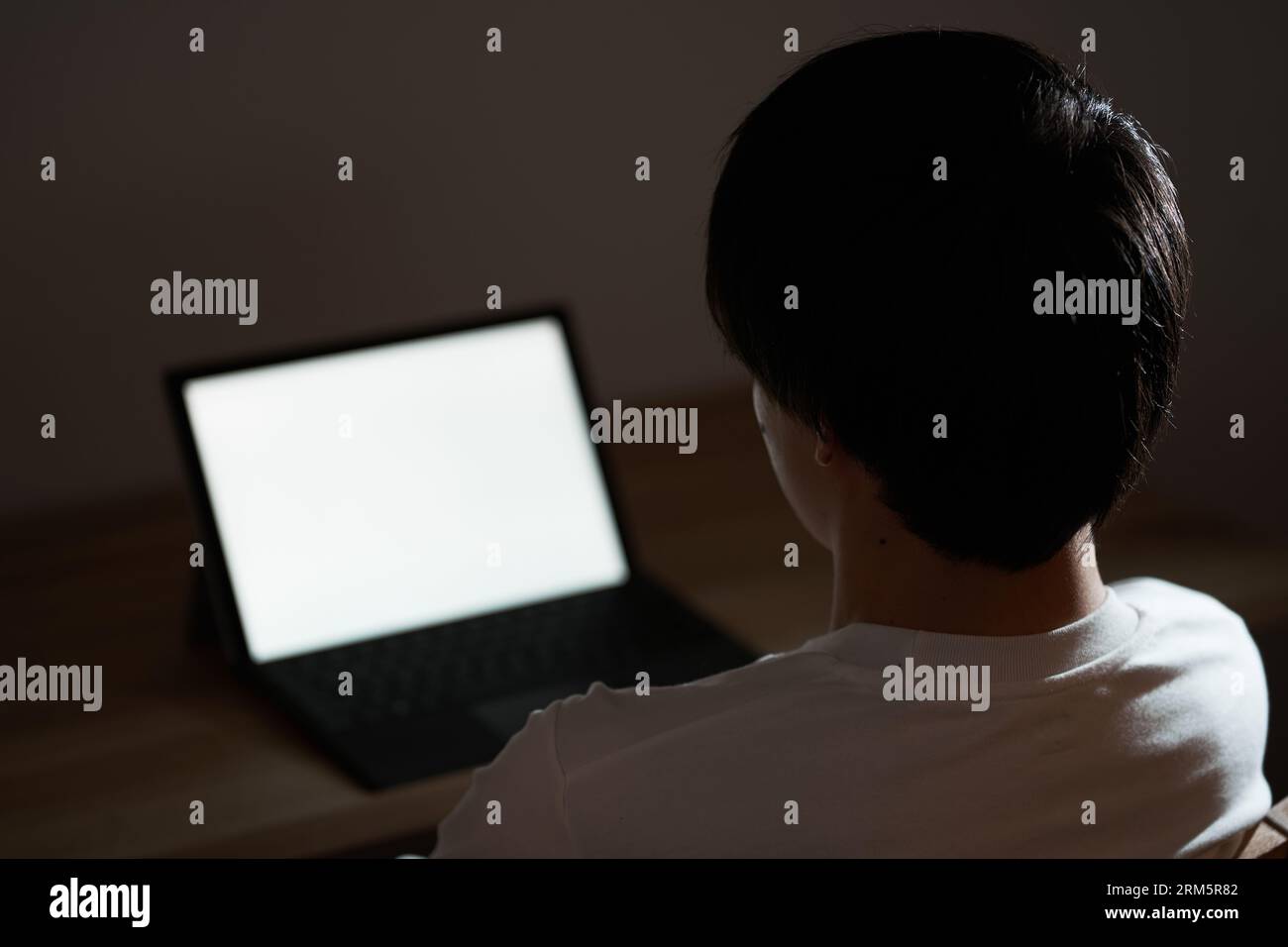 Un uomo asiatico che si dirige verso un portatile nel cuore della notte Foto Stock