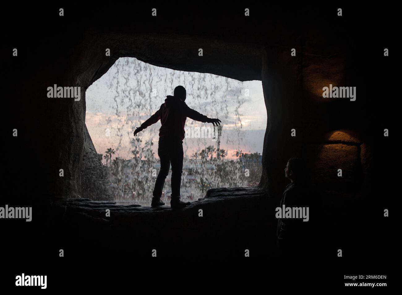 Un uomo posa per delle foto di fronte a una cascata artificiale nel Dream Park, un parco divertimenti situato nel sud-ovest del Cairo, capitale dell'Egitto, il 5 gennaio 2014. Il parco ha attratto famiglie locali e visitatori stranieri con decorazioni natalizie e Capodanno e sconti sui biglietti. (Xinhua/Pan Chaoyue) EGITTO-CAIRO-VITA QUOTIDIANA-INTRATTENIMENTO PUBLICATIONxNOTxINxCHN un uomo posa per le foto di fronte alla cascata artificiale nel Dream Park al parco divertimenti situato nella capitale sud-occidentale del Cairo dell'Egitto IL 5 gennaio 2014 il parco ha attratto famiglie locali e visitatori stranieri con Natale Foto Stock