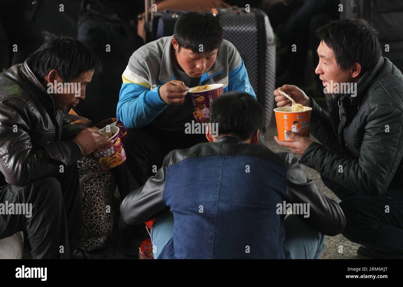 (140118) -- SHANGHAI, 18 gennaio 2014 (Xinhua) -- il passeggero li Jianfu (1st R) mangia spaghetti istantanei alla stazione ferroviaria di Shanghai, East China S Shanghai, 18 gennaio 2014. Un viaggio in treno a lunga distanza non può scoraggiare il desiderio delle persone di riunirsi con i familiari durante il capodanno lunare cinese. Hanno provato tutti i mezzi per ottenere un biglietto per tornare alla città natale prima del festival. (Xinhua/Ding Ting) (cjq) CINA-SHANGHAI-LUNAR NEW YEAR TRAVEL RUSH (CN) PUBLICATIONxNOTxINxCHN Shanghai Jan 18 2014 XINHUA passeggero sinistro 1 ° mangia Instant Noodles ALLA stazione ferroviaria di Shanghai East China S Foto Stock