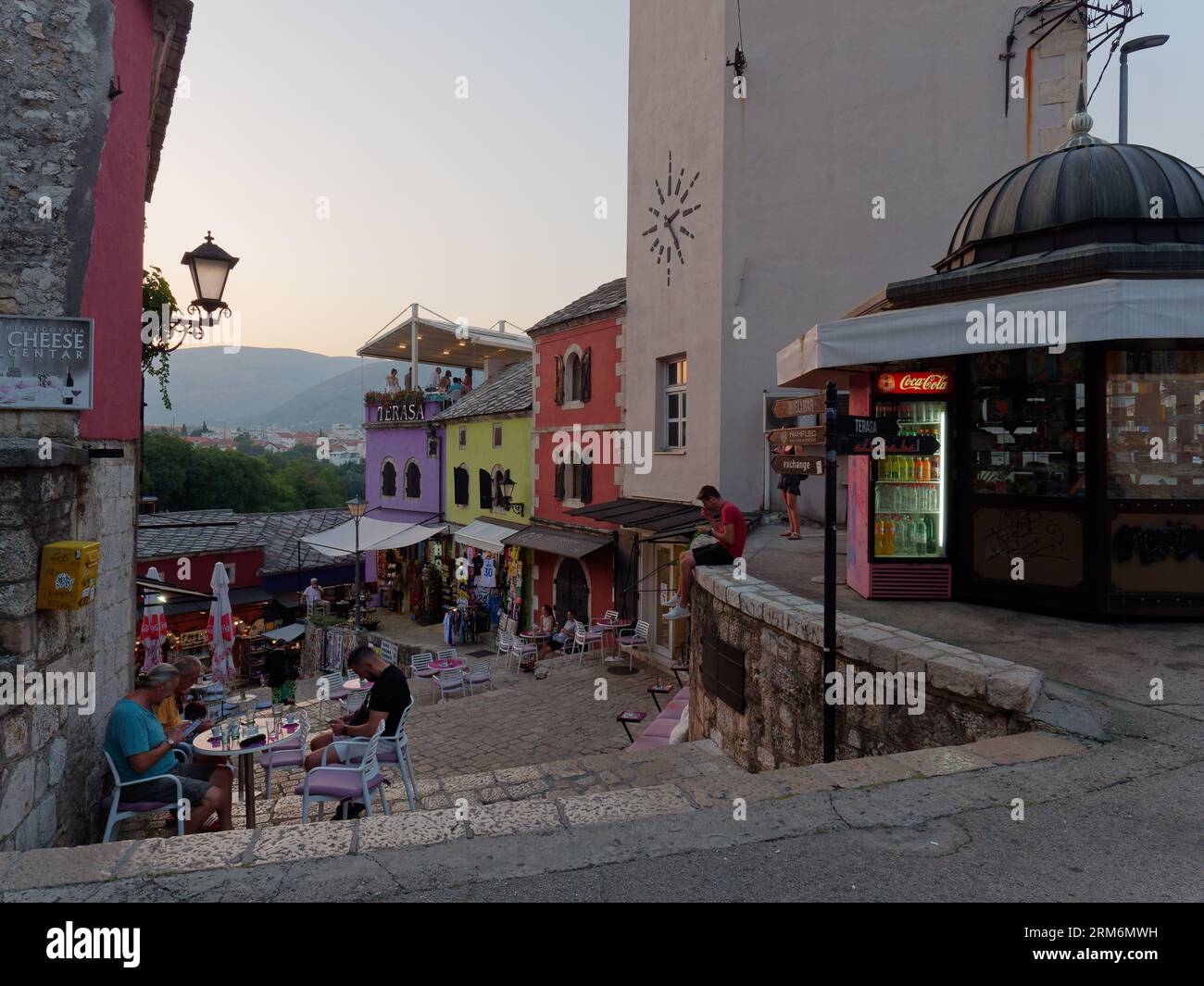 Persone fuori da un caffè nella colorata città vecchia di Mostar e sito UNESCO in estate. Bosnia ed Erzegovina, 26 agosto 2023. Foto Stock