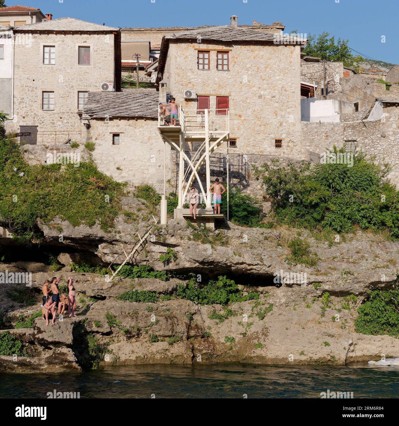Persone che saltano da una piattaforma di addestramento subacqueo sul fiume Neretva nella città di Mostar, Bosnia ed Erzegovina, 25 agosto 2023. Foto Stock