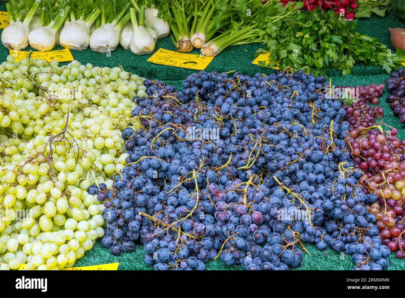 Uva rossa e bianca con alcune verdure in vendita al mercato Foto Stock
