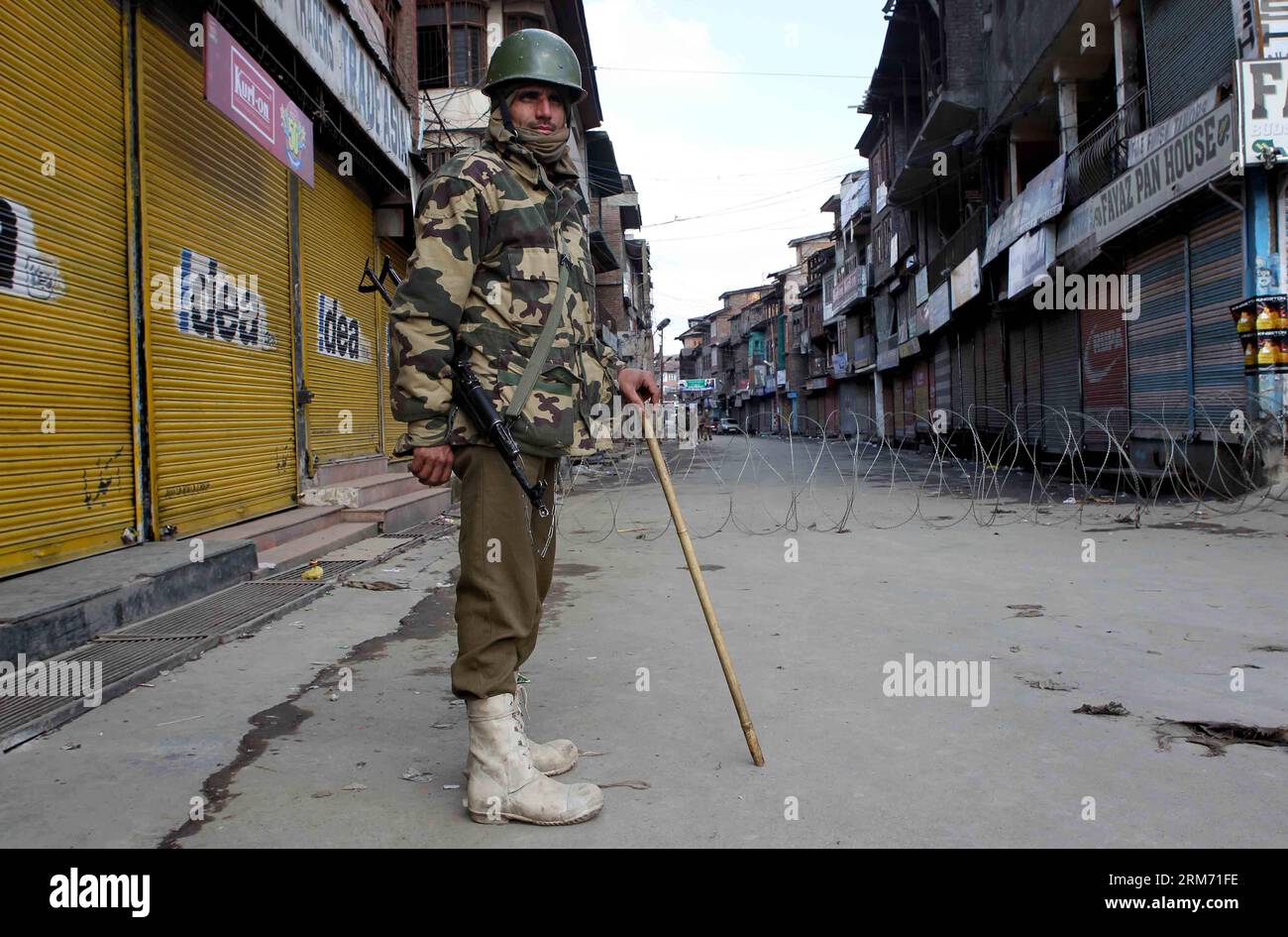 (140209) -- SRINAGAR, 9 febbraio 2014 (Xinhua) -- un gruppo paramilitare indiano si trova a guardia in un mercato chiuso durante le restrizioni a Srinagar, la capitale estiva del Kashmir controllato dagli indiani, 9 febbraio 2014. Le autorità domenica hanno imposto restrizioni nelle aree dominate dai musulmani del Kashmir controllato dagli indiani per prevenire proteste e scontri nel primo anniversario dell'esecuzione di Mohammed Afzal Guru condannato per attacco al parlamento indiano, hanno detto i funzionari. (Xinhua/Javed Dar) KASHMIR-SRINAGAR-PROTEST PUBLICATIONxNOTxINxCHN Srinagar 9 febbraio 2014 XINHUA a Indian paramilitare Trooper sta di guardia in una M chiusa Foto Stock