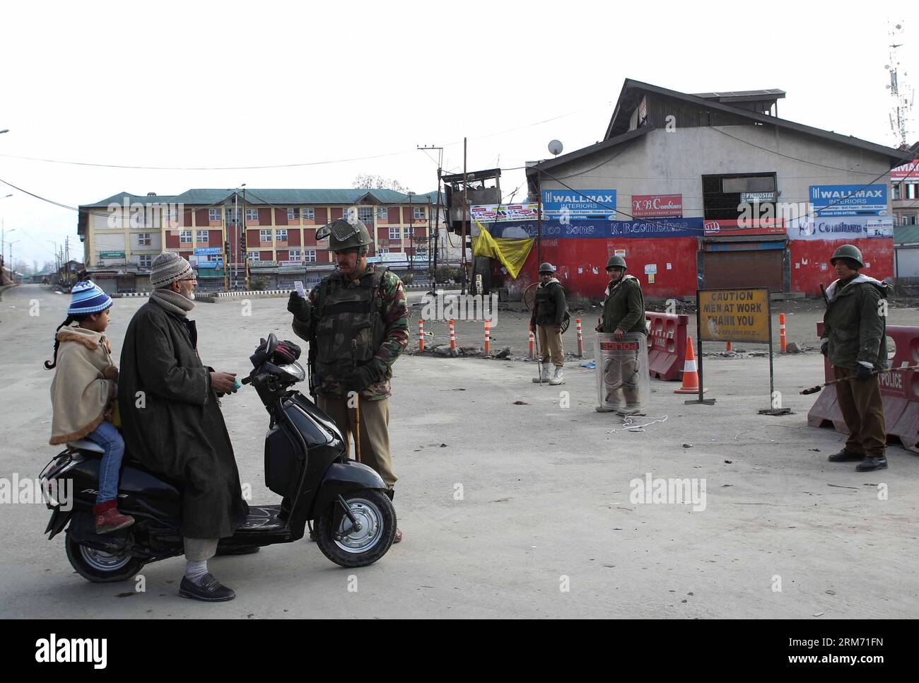 (140209) -- SRINAGAR, 9 Feb. 2014 (Xinhua) -- un equipaggio paramilitare indiano controlla la carta di un uomo vicino a una barricata durante le restrizioni a Srinagar, la capitale estiva del Kashmir controllato dagli indiani, 9 Feb. 2014. Le autorità domenica hanno imposto restrizioni nelle aree dominate dai musulmani del Kashmir controllato dagli indiani per prevenire proteste e scontri nel primo anniversario dell'esecuzione di Mohammed Afzal Guru condannato per attacco al parlamento indiano, hanno detto i funzionari. (Xinhua/Javed Dar) KASHMIR-SRINAGAR-PROTEST PUBLICATIONxNOTxINxCHN Srinagar 9 febbraio 2014 XINHUA a Indian paramilitary Trooper Checks Card of a Man Foto Stock