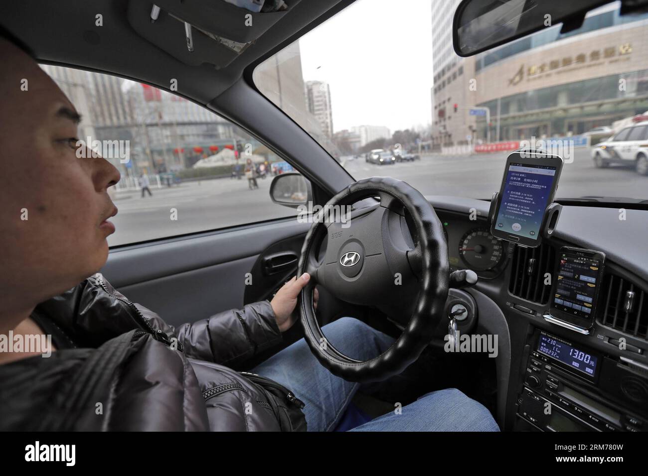 (140218) - PECHINO, 18 febbraio 2014 (Xinhua) - Un tassista utilizza sia Didi che KuaiDi, app di chiamata in taxi su due smartphone per trovare più clienti a Pechino, capitale della Cina, 18 febbraio 2014. Alipay, la più grande piattaforma di pagamento online di terze parti del paese e una filiale del gruppo Alibaba, ha investito pesantemente nell'app KuaiDi per i sussidi di pagamento per promuovere il proprio servizio di pagamento online. La mossa è nata sulla scia di un analogo programma di sovvenzioni da parte dell'app Didi, con investimenti da parte di Tencent. L'incentivo di Didi, annunciato all'inizio di gennaio, incoraggia i passeggeri a pagare le tariffe dei taxi tramite TEN Foto Stock