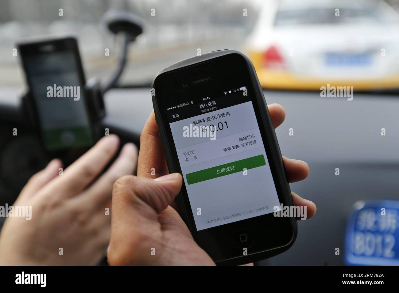 (140218) -- PECHINO, 18 febbraio 2014 (Xinhua) -- Un giornalista usa Didi, un'app di taxi-hailing per pagare solo 0,01 yuan per il conto a causa dell'elevato sussidio a Pechino, capitale della Cina, 18 febbraio 2014. Alipay, la più grande piattaforma di pagamento online di terze parti del paese e una filiale del gruppo Alibaba, ha investito pesantemente nell'app KuaiDi per i sussidi di pagamento per promuovere il proprio servizio di pagamento online. La mossa è nata sulla scia di un analogo programma di sovvenzioni da parte dell'app Didi, con investimenti da parte di Tencent. L'incentivo di Didi, annunciato all'inizio di gennaio, incoraggia i passeggeri a pagare le tariffe dei taxi via te Foto Stock