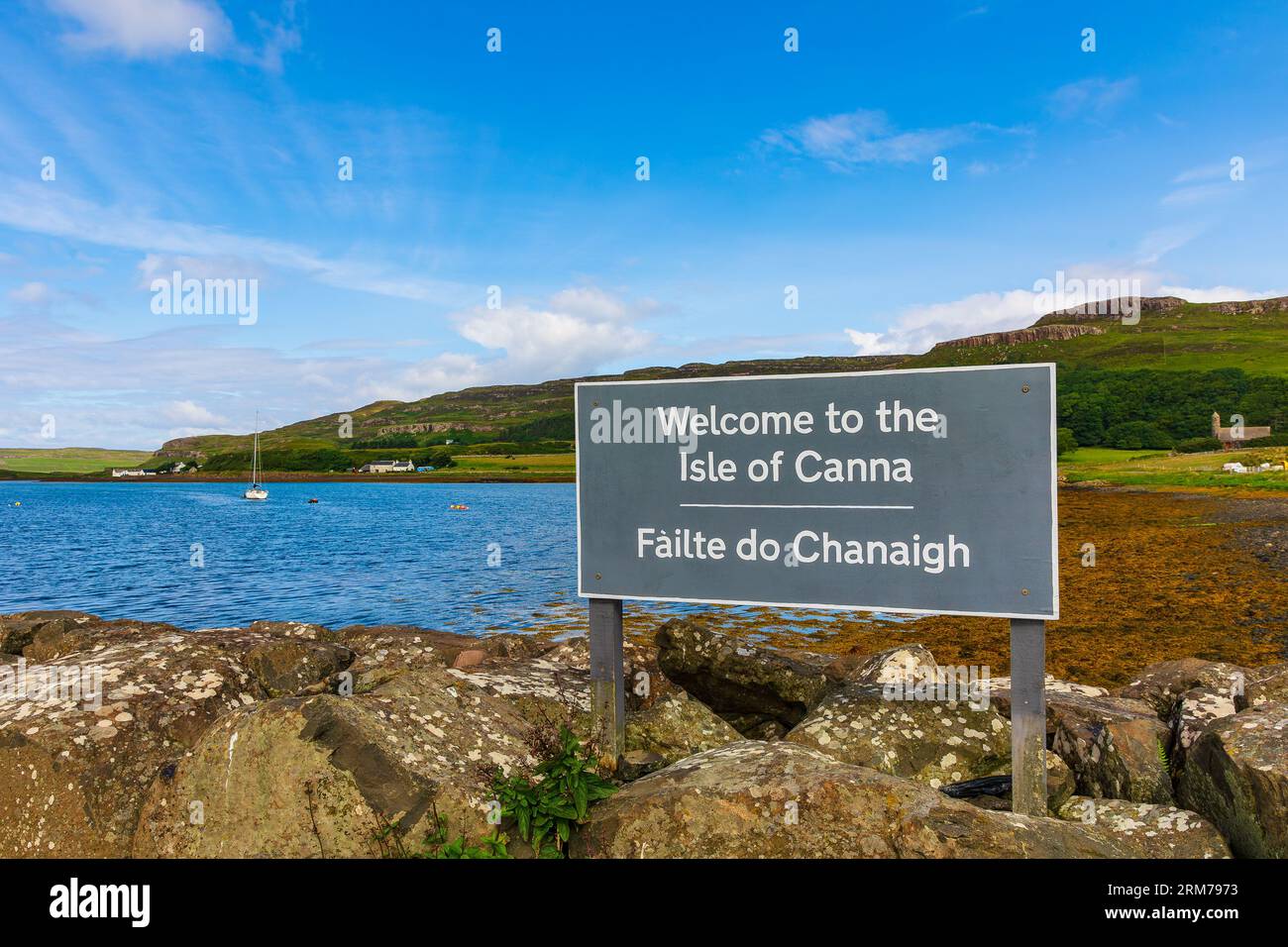 Cartello di benvenuto per l'isola di canna per i visitatori che arrivano sull'isola in traghetto. Sia l'inglese che il gaelico. Small Isles, Ebridi interne, Scozia. Ho Foto Stock