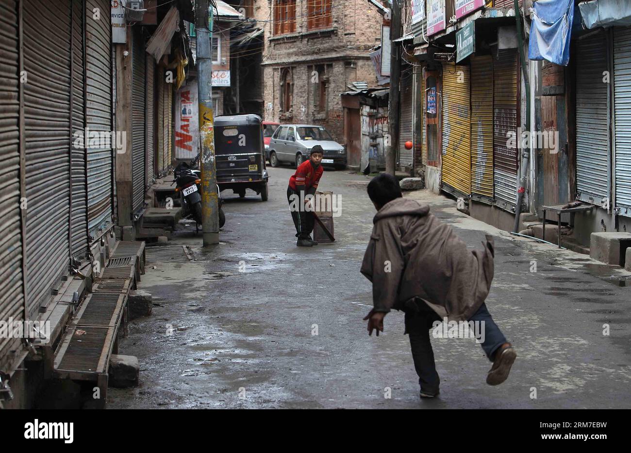 (140228) -- SRINAGAR, 28 febbraio 2014 (Xinhua) -- i bambini del Kashmir giocano a cricket in un mercato chiuso durante lo sciopero a Srinagar, capitale estiva del Kashmir controllato dagli indiani, il 28 febbraio 2014. Un arresto è stato osservato dalle aree a maggioranza musulmana del Kashmir controllato dagli indiani in seguito alla chiamata dei gruppi separatisti del Kashmir che cercavano l'identificazione di sette sospetti militanti uccisi dall'esercito indiano lunedì nel distretto di Kupwara, a circa 125 km a nord-ovest della città di Srinagar. Le proteste scoppiarono nella zona dopo che i civili sostenevano che gli uomini uccisi fossero civili. La polizia non ha identificato la vittima Foto Stock