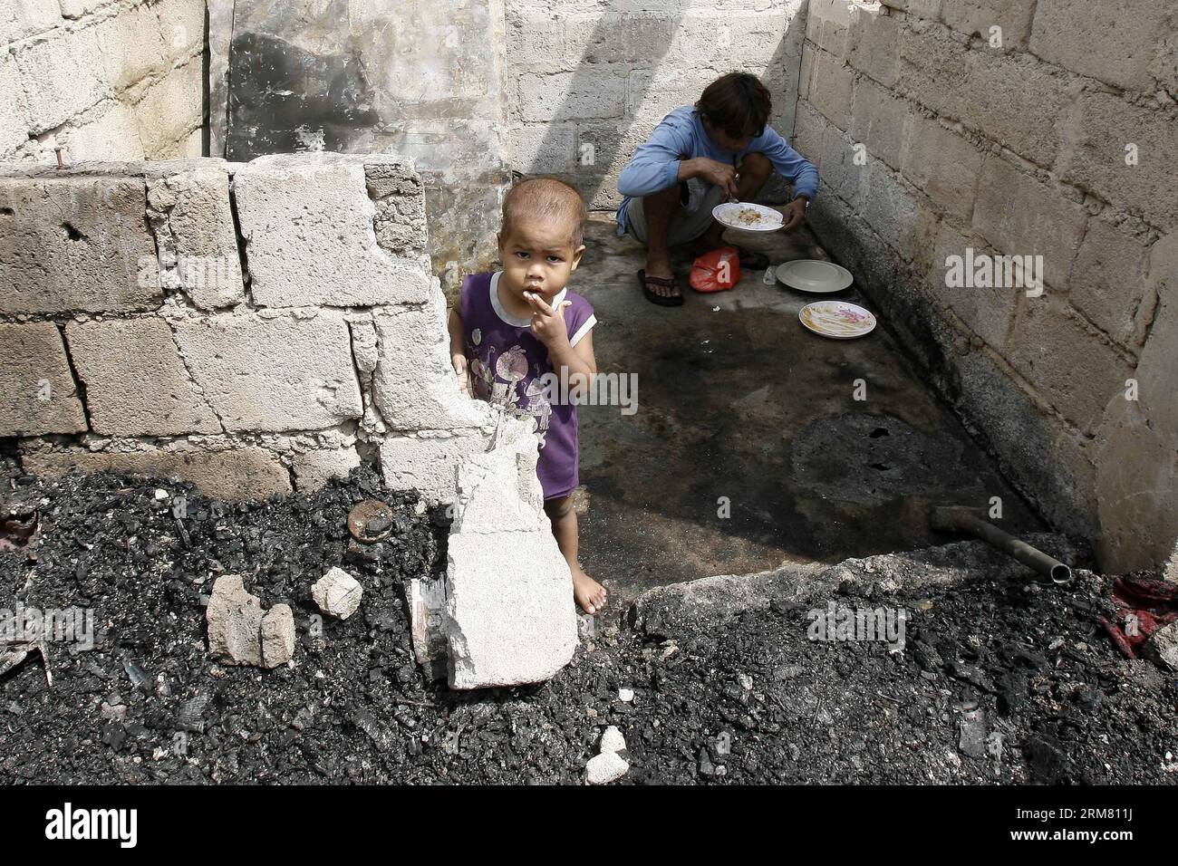 I residenti mangiano all'interno della loro casa bruciata dopo un incendio in un'area slum a Manila, nelle Filippine, il 23 marzo 2014. Il Philippine Bureau of Fire Protection stimò che circa 200 - 300 case furono rase al suolo dall'incendio, colpendo più di 1.000 famiglie nell'area. (Xinhua/Rouelle Umali) FILIPPINE-MANILA-FIRE PUBLICATIONxNOTxINxCHN residenti mangiano nella loro casa bruciata dopo un incendio IN una zona di baraccopoli a Manila nelle Filippine 23 marzo 2014 il Philippine Bureau of Fire Protection stimò che Thatcher circa 200 - 300 case furono rase dal fuoco che colpì più di 1 000 famiglie nell'area XINH Foto Stock