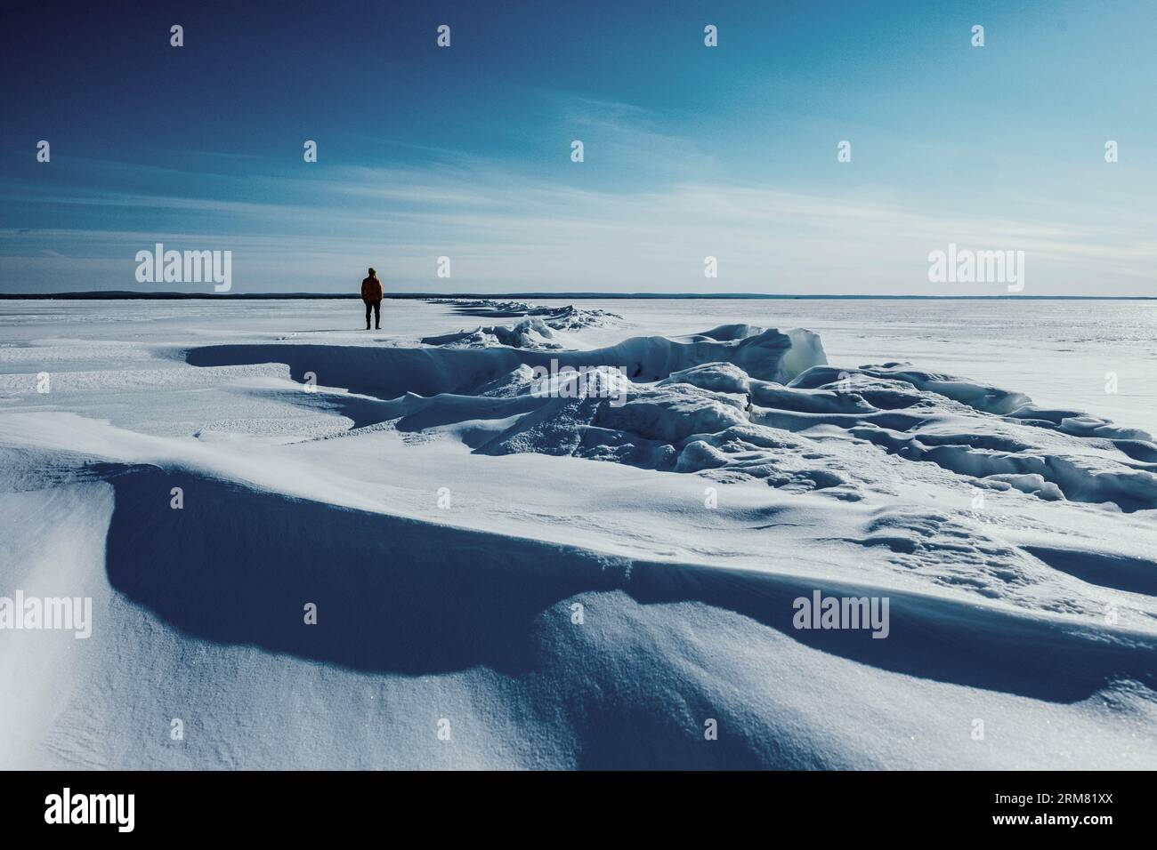 Un'immagine grandangolare di una persona che si staglia su un paesaggio ghiacciato e innevato Foto Stock
