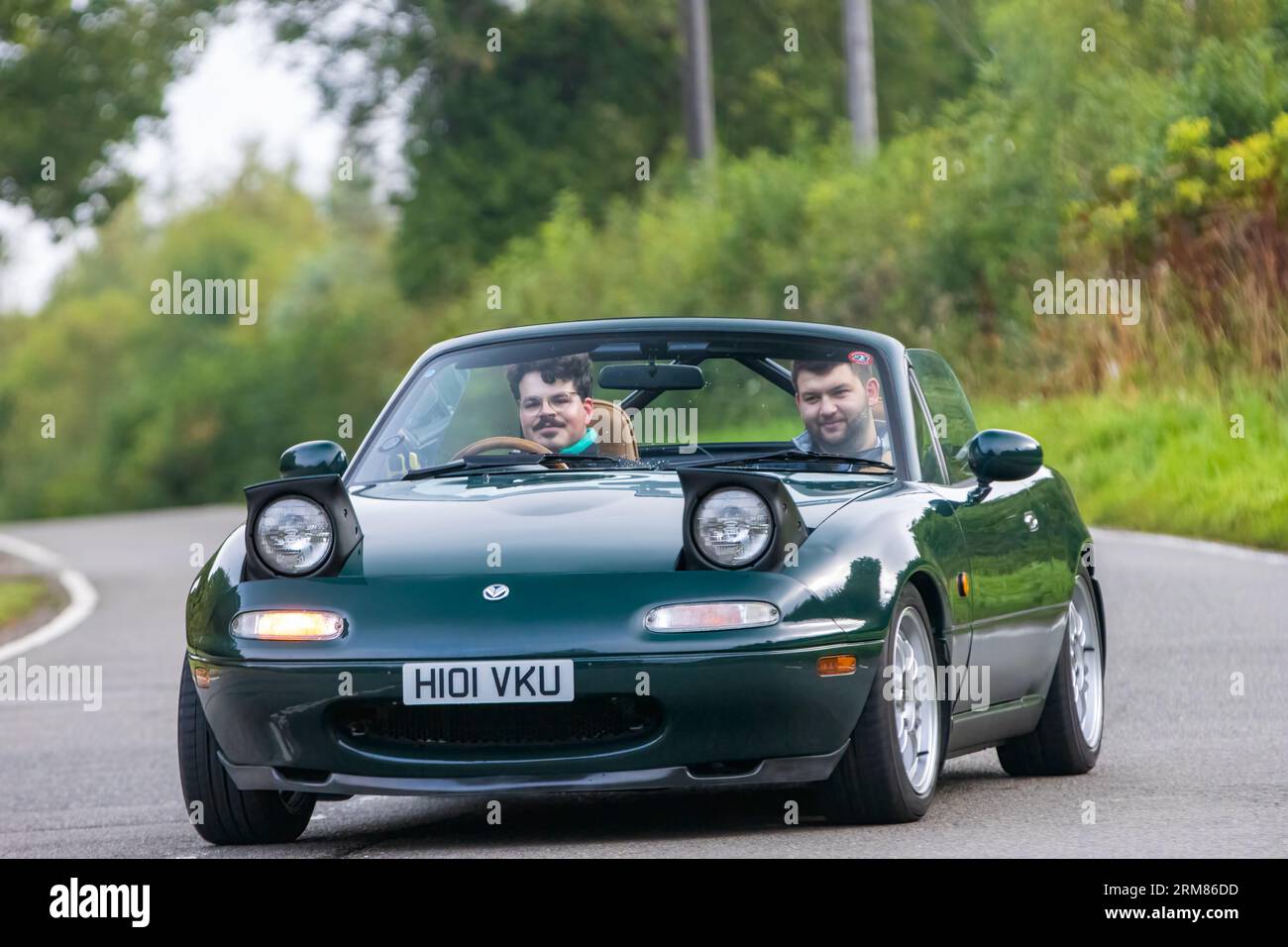 Whittlebury, Northants, Regno Unito - 26 agosto 2023: 1990 auto sportiva Mazda MX 5 verde con fari a scomparsa che viaggiano su una strada di campagna inglese Foto Stock