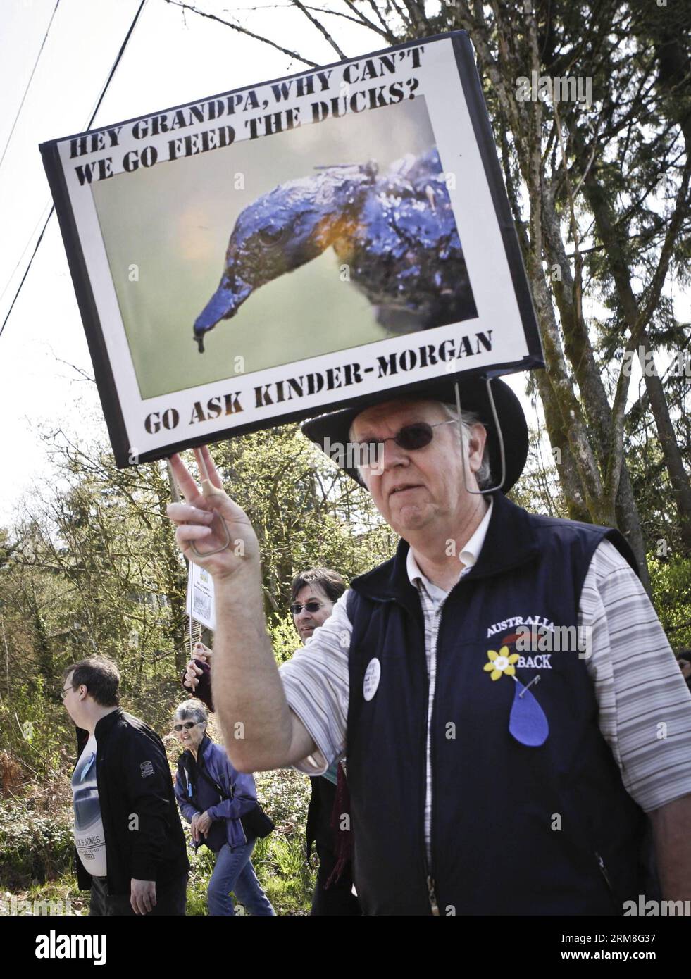 Un uomo ha una foto di un'anatra coperta di petrolio in una protesta al raduno anti-oleodotto a Burnaby, Canada, il 12 aprile 2014. Circa 300 residenti Burnaby insieme agli ambientalisti hanno partecipato a una manifestazione per protestare contro i piani della compagnia petrolifera Kinder Morgan di espandere un oleodotto nelle aree residenziali che aumenta il rischio di salute e sicurezza nonché l'ambiente naturale. (Xinhua/Liang Sen) CANADA-VANCOUVER-PROTESTA-COMPAGNIA PETROLIFERA-ESPANSIONE DELL'OLEODOTTO PUBLICATIONxNOTxINxCHN a Man Holds a Picture of a Duck Covered with Oil in una protesta AL raduno anti-oleodotti di Burnaby Canada ON Foto Stock