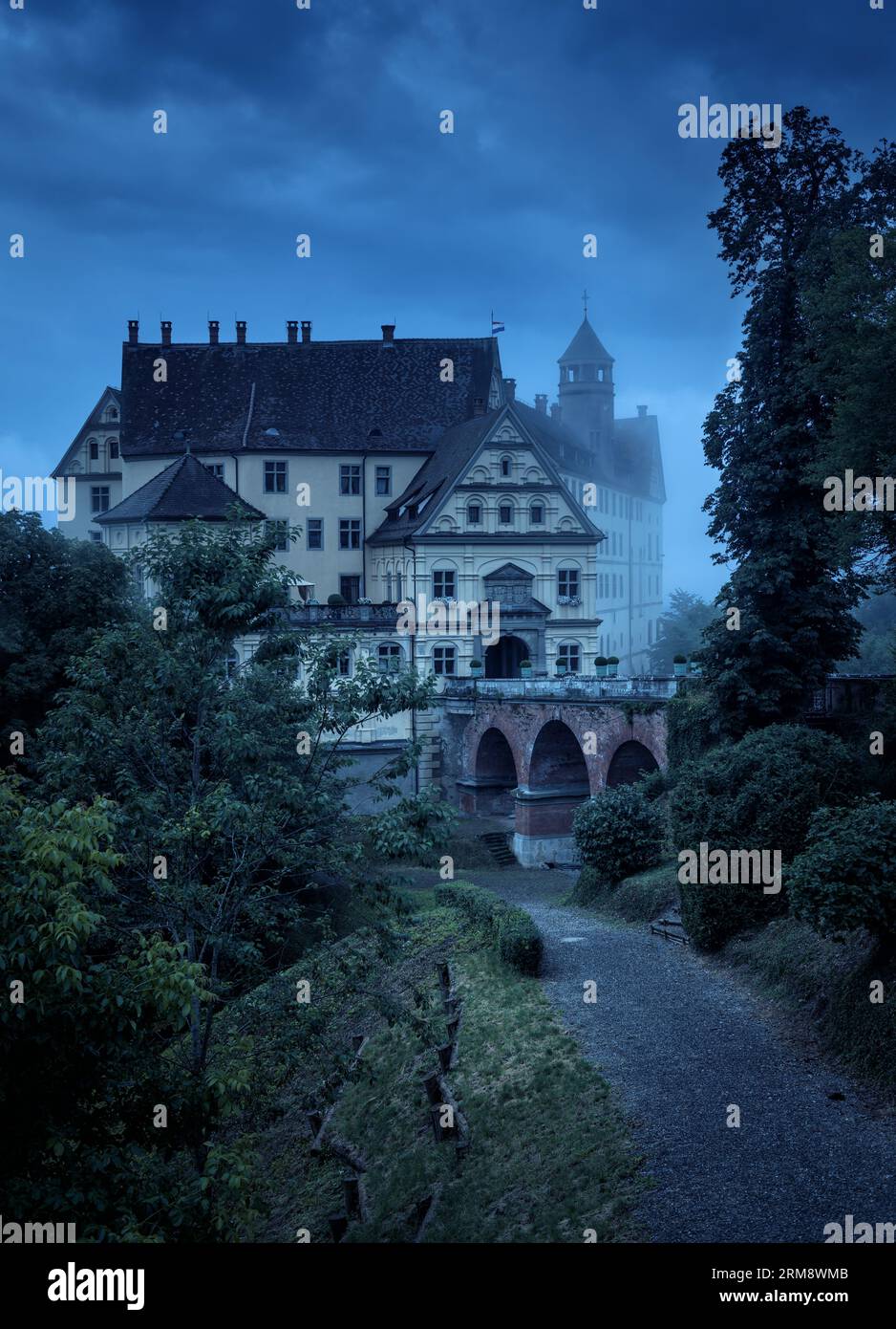 Castello infestato dalla nebbia durante la notte di Halloween, vecchia villa spettrale al crepuscolo. Vista verticale del castello scuro con crepuscolo mistico blu. Scena cupa, mistero e.. Foto Stock