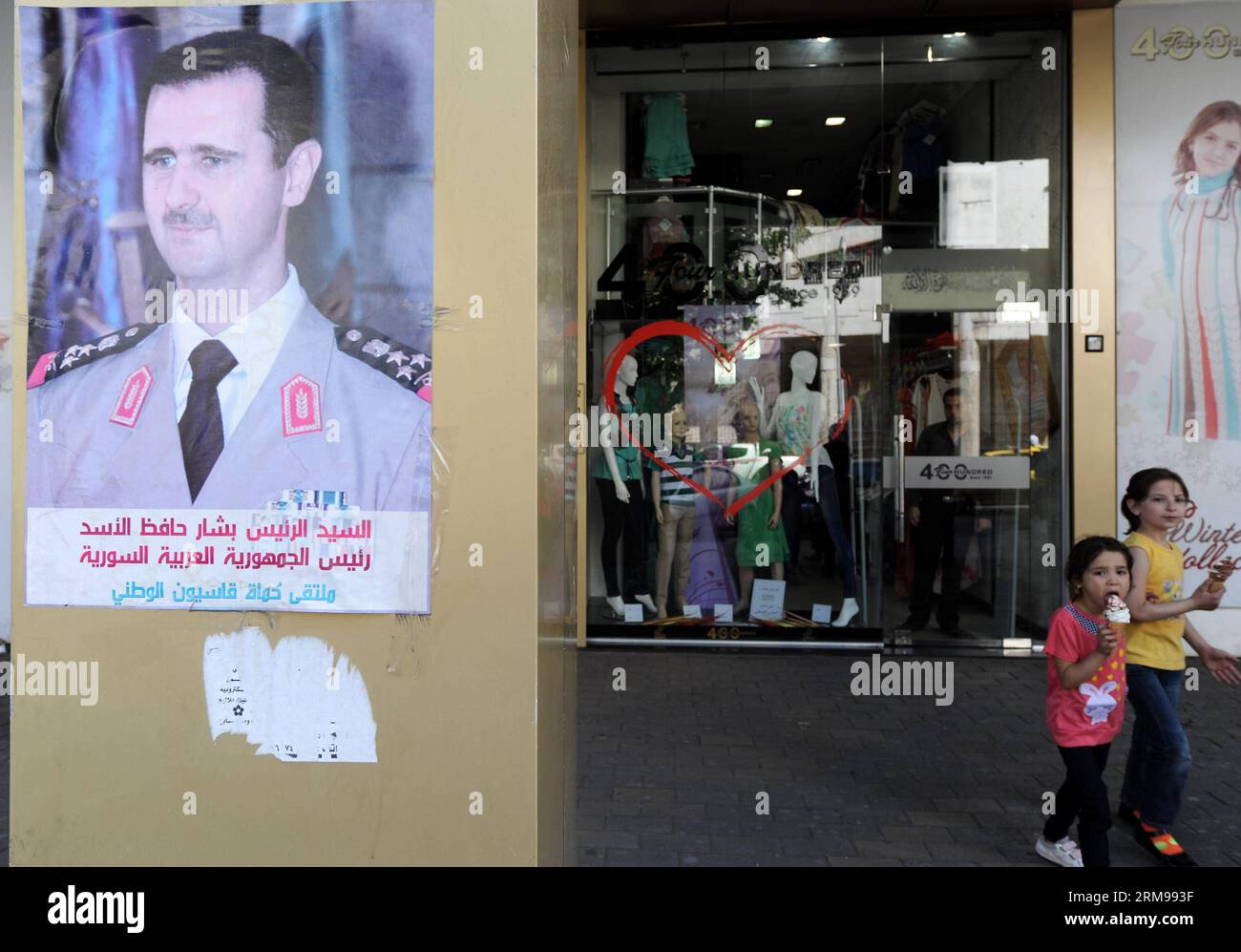 DAMASCO, 13 maggio 2014 - un poster della campagna elettorale del presidente in carica Bashar al-Assad è stato visto sul muro di un negozio a Damasco, capitale della Siria, 13 maggio 2014. Manifesti e striscioni dei tre candidati presidenziali siriani decorano le strade principali di Damasco, con il presidente in carica Bashar al-Assad che, prevedibilmente, ha ricevuto la quota di leone della pubblicità, mentre la campagna per le elezioni inizierà il 12 maggio. La Corte costituzionale suprema della Siria ha accettato la candidatura di tre contendenti, tra cui Maher Abdul-Hafiz Hajjar, Hassan Abdullah al-Nouri e Bashar al-Assad, per il 3 giugno p Foto Stock