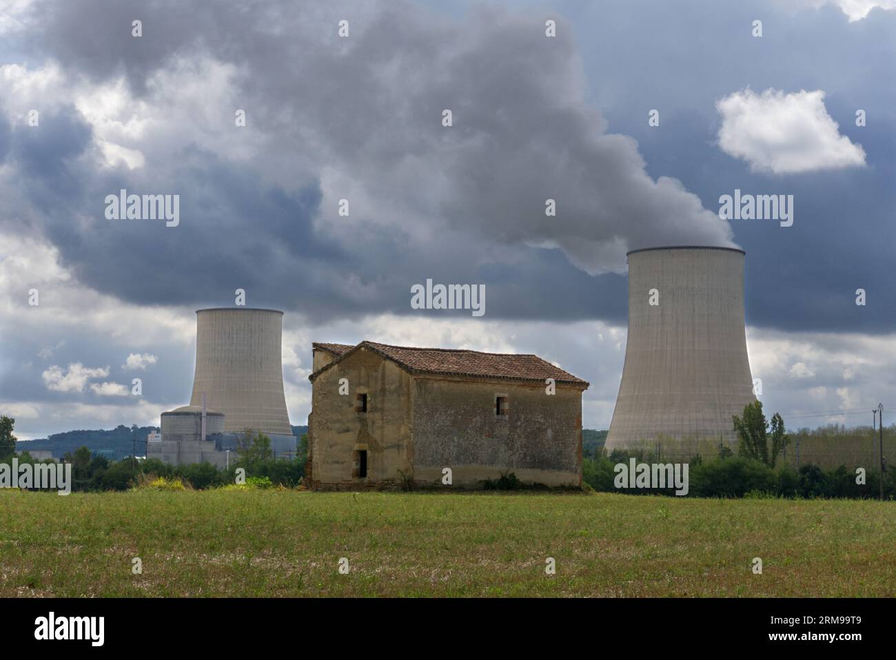 Una tradizionale casa in pietra di fronte a una centrale nucleare da qualche parte in Francia. Sky è buio e drammatico. Spazio per il copyright disponibile. Foto Stock
