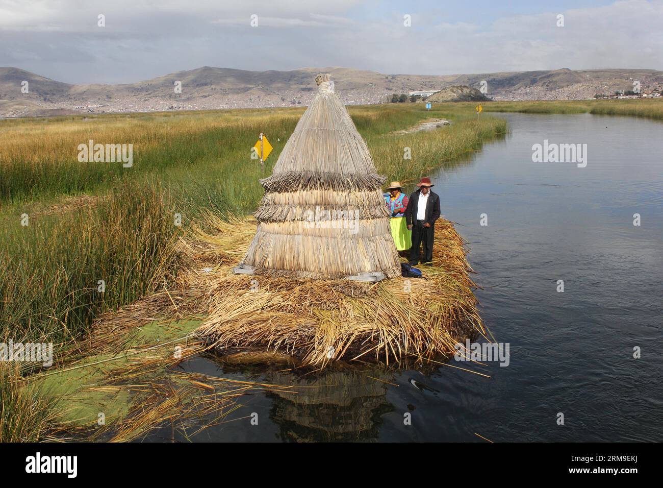 (140520) -- PUNO, 20 maggio 2014 (Xinhua) -- la gente si trova accanto a una casa sull'isola galleggiante di Los Uros sul lago Titicaca, nella regione di Puno, Perù, 13 maggio 2014. Il lago Titicaca e le sue isole galleggianti nella regione di Puno del Perù hanno non solo attrazioni naturali, ma anche una cultura unica grazie alla popolazione quechua di Juliaca che vive lì. Il lago Titicaca si trova nell'altopiano di Collao, con le isole di Luna, Taquile, Amantani, Uros e Suriqui. (Xinhua/Luis Camacho)(zhf) PERU-PUNO-TITICACA LAKE-FLOATING ISLAND PUBLICATIONxNOTxINxCHN Puno 20 maggio 2014 le celebrità di XINHUA si trovano accanto a una casa Foto Stock