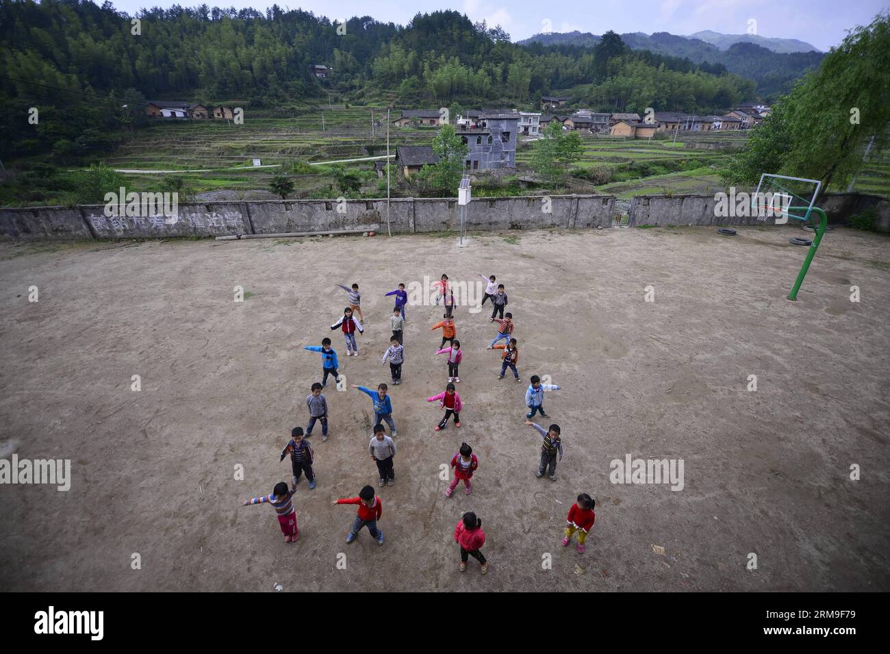 Gli studenti fanno esercizi fisici nel parco giochi della Liyuan Elementary School nel villaggio di Xikeng sotto la contea di Wanzai di Yichun, nella provincia orientale del Jiangxi della Cina, 20 maggio 2014. La mancanza di insegnanti qualificati è stata un problema onnipresente che affligge molte scuole elementari della Cina rurale. Le autorità educative della contea di Wanzai hanno lanciato un programma di formazione per insegnanti quinquennale nel 2014 per soddisfare la domanda di insegnanti nelle aree rurali della contea. Ogni anno, il programma riceverà 30 candidati junior-high provenienti da zone rurali. La metà dei richiedenti è tenuta a lavorare nelle scuole rurali quando t Foto Stock