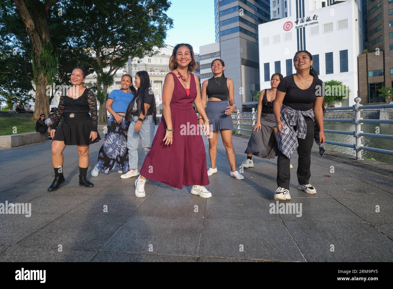 Nella loro domenica libera, le filippine impiegate come cameriere di casa praticano la danza si spostano verso una colonna sonora di Bollywood; at Boat Quay by the Singapore Rive, Singapore Foto Stock