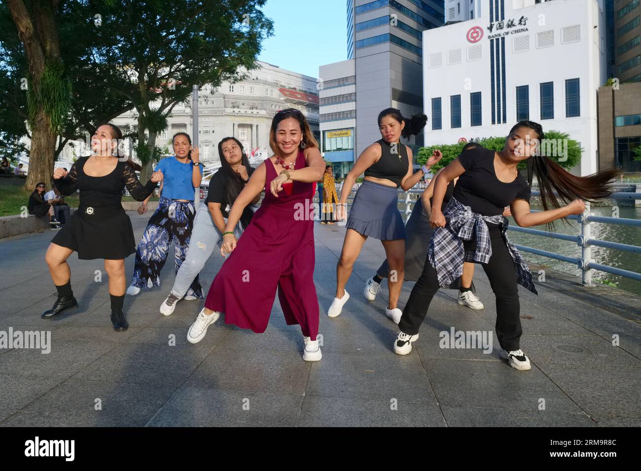 Nella loro domenica libera, le filippine impiegate come cameriere di casa praticano la danza si spostano verso una colonna sonora di Bollywood; at Boat Quay by the Singapore Rive, Singapore Foto Stock