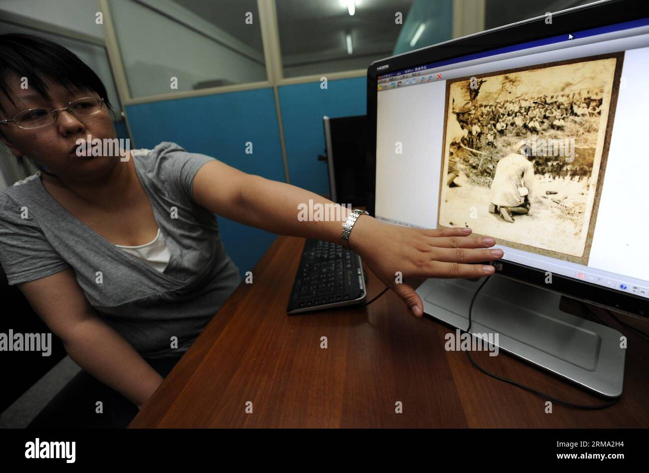 (140612) -- NANCHINO, 12 giugno 2014 (Xinhua) -- Un membro dello staff presenta foto scattate dagli invasori giapponesi sul massacro di Nanchino presso il secondo Archivio storico della Cina a Nanchino, capitale della provincia di Jiangsu della Cina orientale, 12 giugno 2014. La Cina sta chiedendo all'UNESCO di elencare 11 serie di documenti relativi al massacro di Nanchino del 1937 sulla memoria del Registro mondiale. I documenti, che includono diari, film, fotografie e testimonianze, raffigurano la brutalità degli invasori giapponesi nel massacro. (Xinhua/Han Yuqing) (zc) CINA-JIANGSU-NANJING MASSACRO-MEMORIA DEL REGISTRO MONDIALE-BI Foto Stock